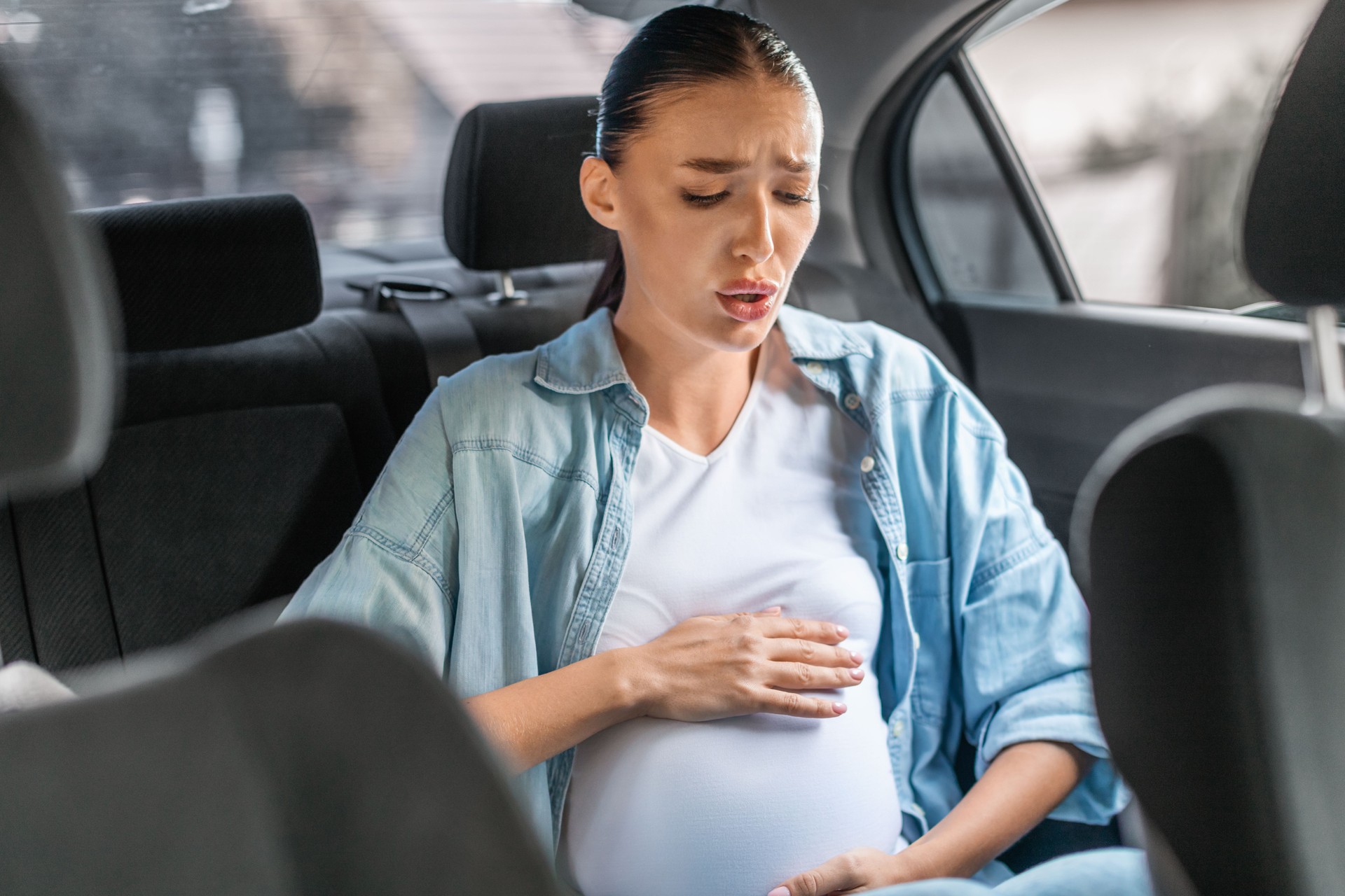 pregnant woman experiencing Braxton Hicks contractions sitting in car