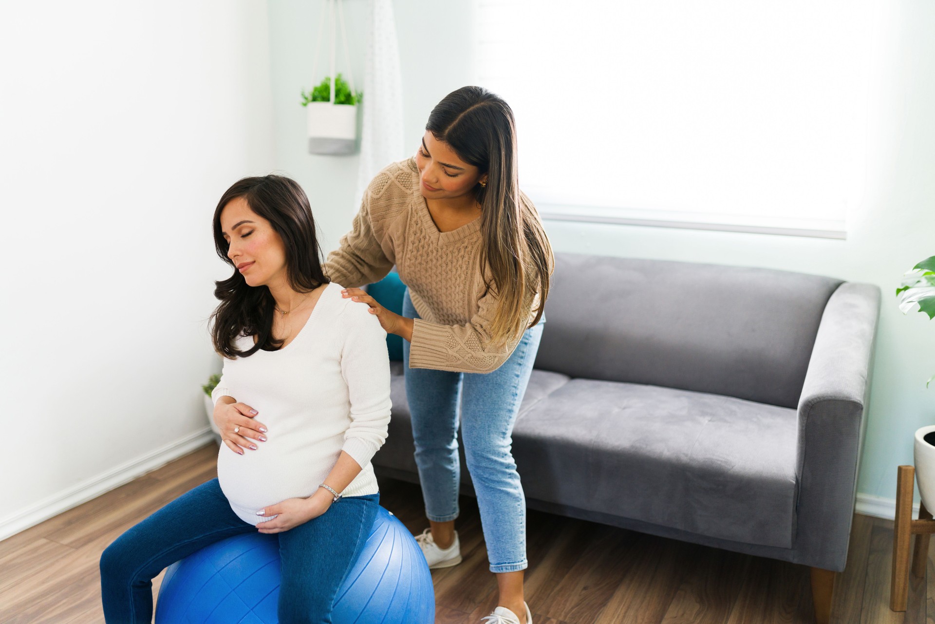 Latin doula massaging the shoulders of a pregnant woman